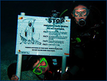 Two students pose with a sign meant to discourage recreational swimmers and snorkelers from entering the caves